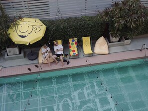 A poolside area with lounge chairs, a yellow umbrella, and a hedge in the background. - Josh Hotel (Bangkok)