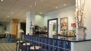 Un espace bar doté d’un comptoir en marbre, de tabourets de bar et d’une machine à café.