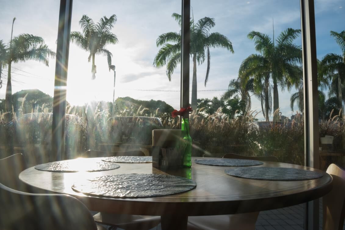 A round table with placemats, a green bottle, and a menu stand.