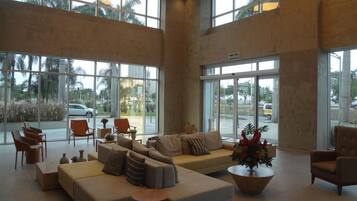A spacious lobby with a large seating area, including sofas and chairs, and large windows offering a view of the outside.
