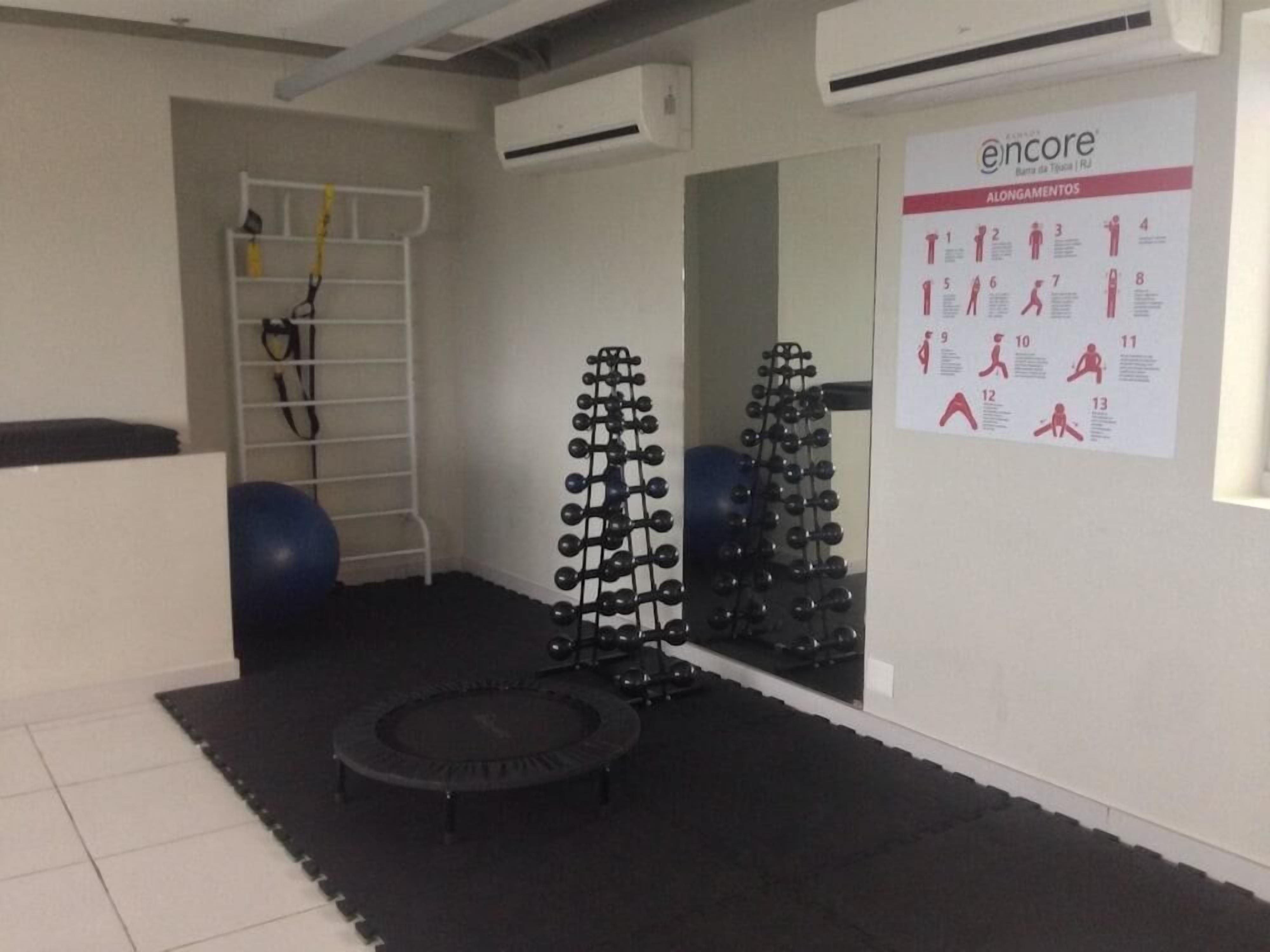 A gym with exercise equipment, a wall-mounted poster with exercise routines, and a small trampoline.