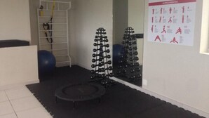 A gym with exercise equipment, a wall-mounted poster with exercise routines, and a small trampoline. - Ribalta Hotel Barra da Tijuca by Atlantica (Rio de Janeiro)