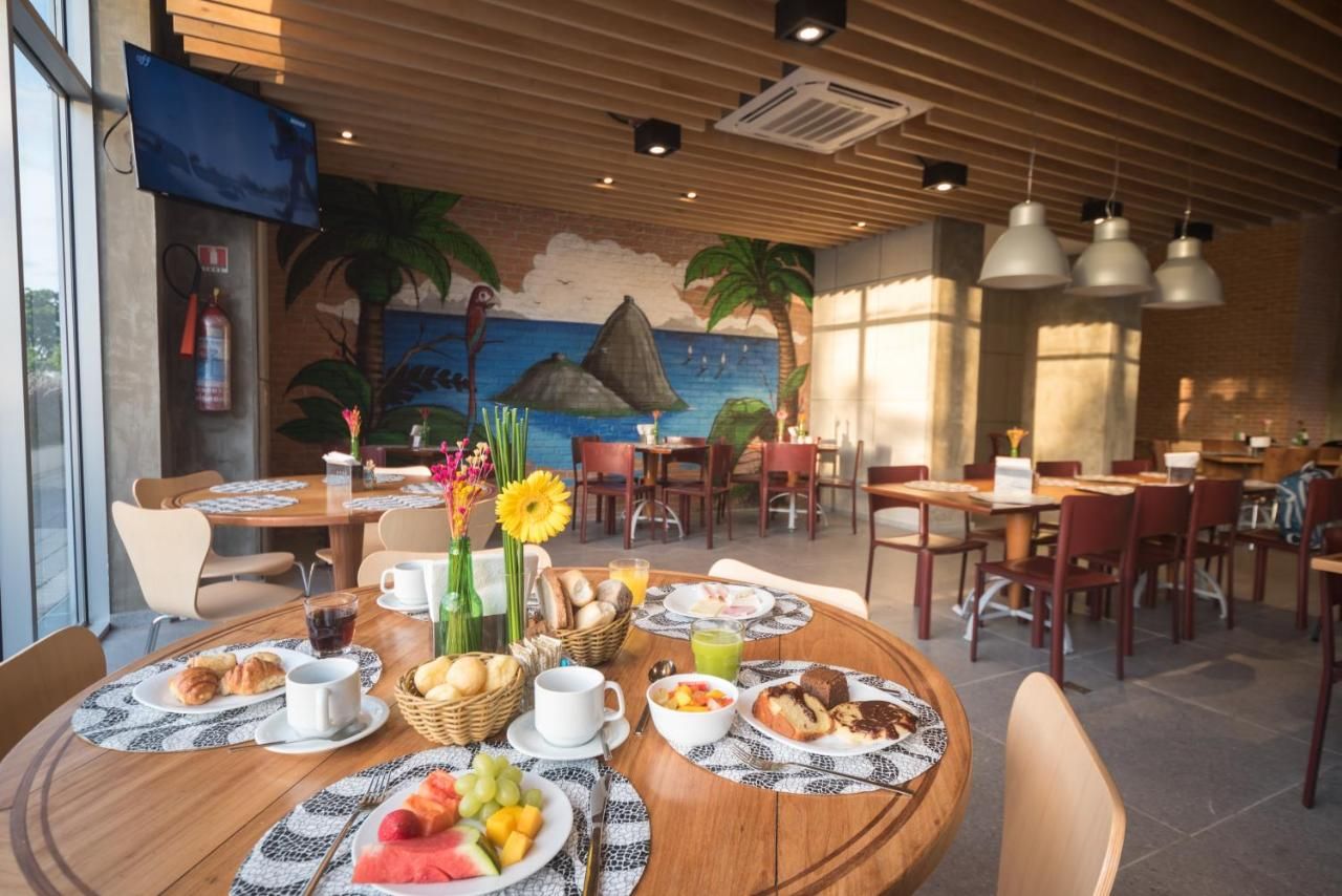 Un restaurante con mesas redondas, sillas y un mural con una escena de playa.