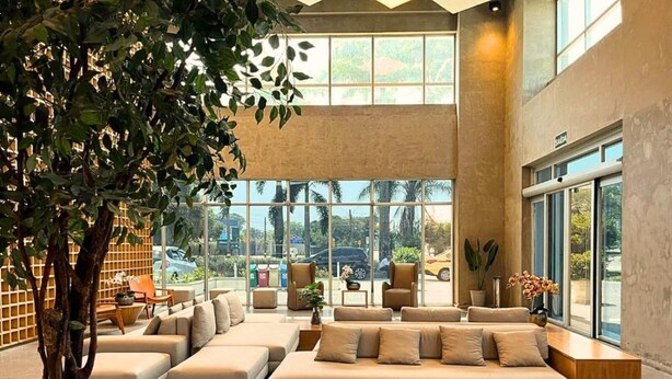 Eine geräumige Lobby mit einer großen Sitzgruppe, einem Baum und großen Fenstern mit Blick nach draußen.