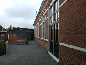 A brick building with large windows and a wooden bench in the courtyard. - Logement de 12e Stad - Private studio in former school near Leeuwarden (Berlikum)