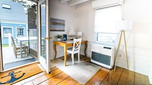 A room with a wooden desk, a white chair, a standing lamp, and an air conditioner. - Charming Vineyard Saltbox + Ferry Tickets (Edgartown)