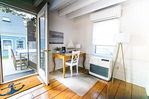 A room with a wooden desk, a white chair, a standing lamp, and an air conditioner.