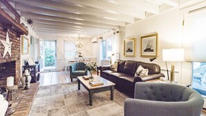 A spacious living room with a fireplace, a sofa, a coffee table, and a view of the outdoors. - Charming Vineyard Saltbox + Ferry Tickets (Edgartown)