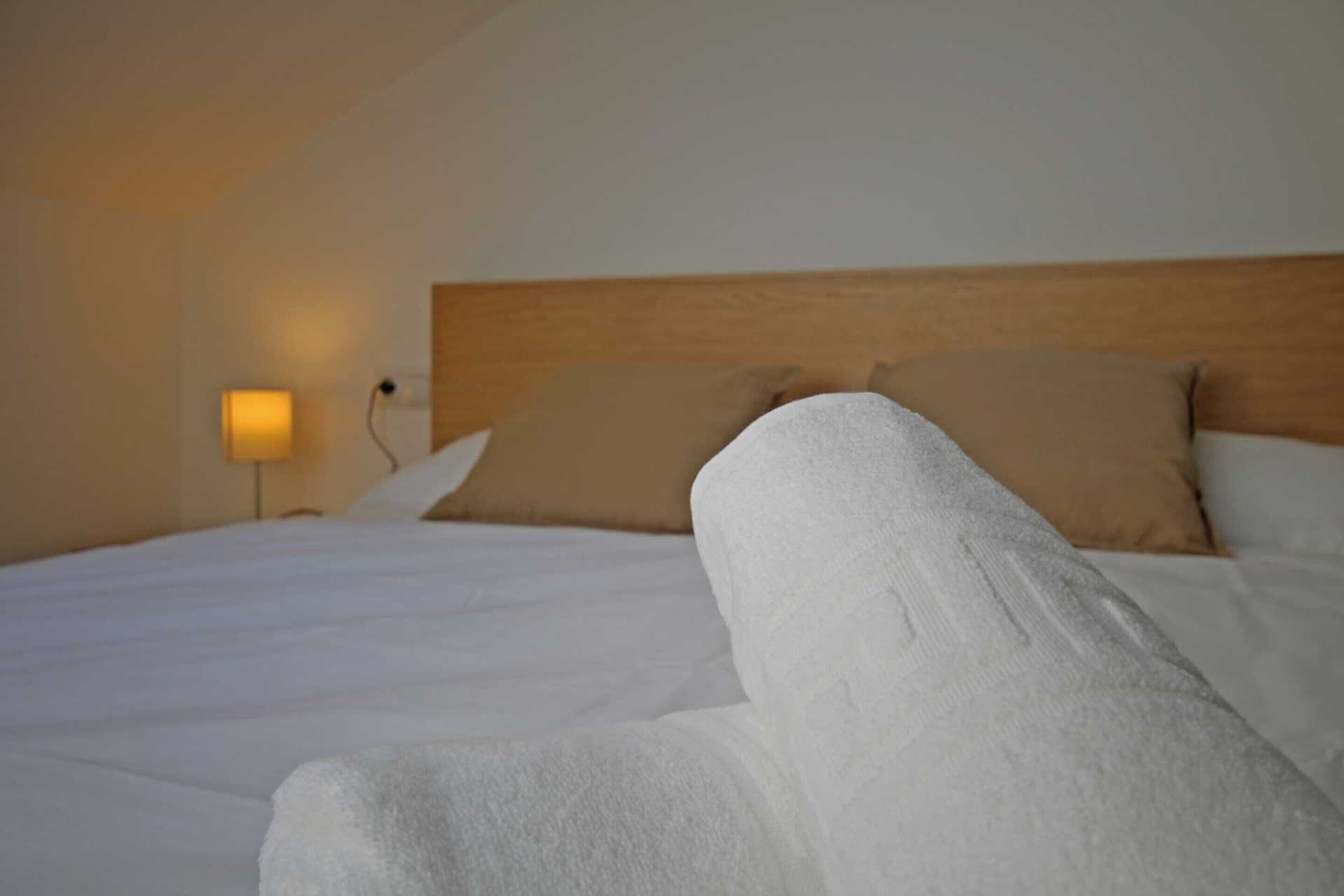Una cama bien hecha con sábanas blancas y un cabecero de madera.