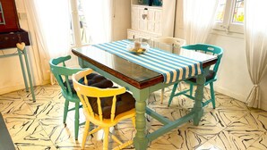 A dining area with a striped tablecloth, teal chairs, and a patterned floor.