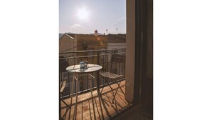 A balcony with a table and chairs, a view of buildings, and a clear sky.