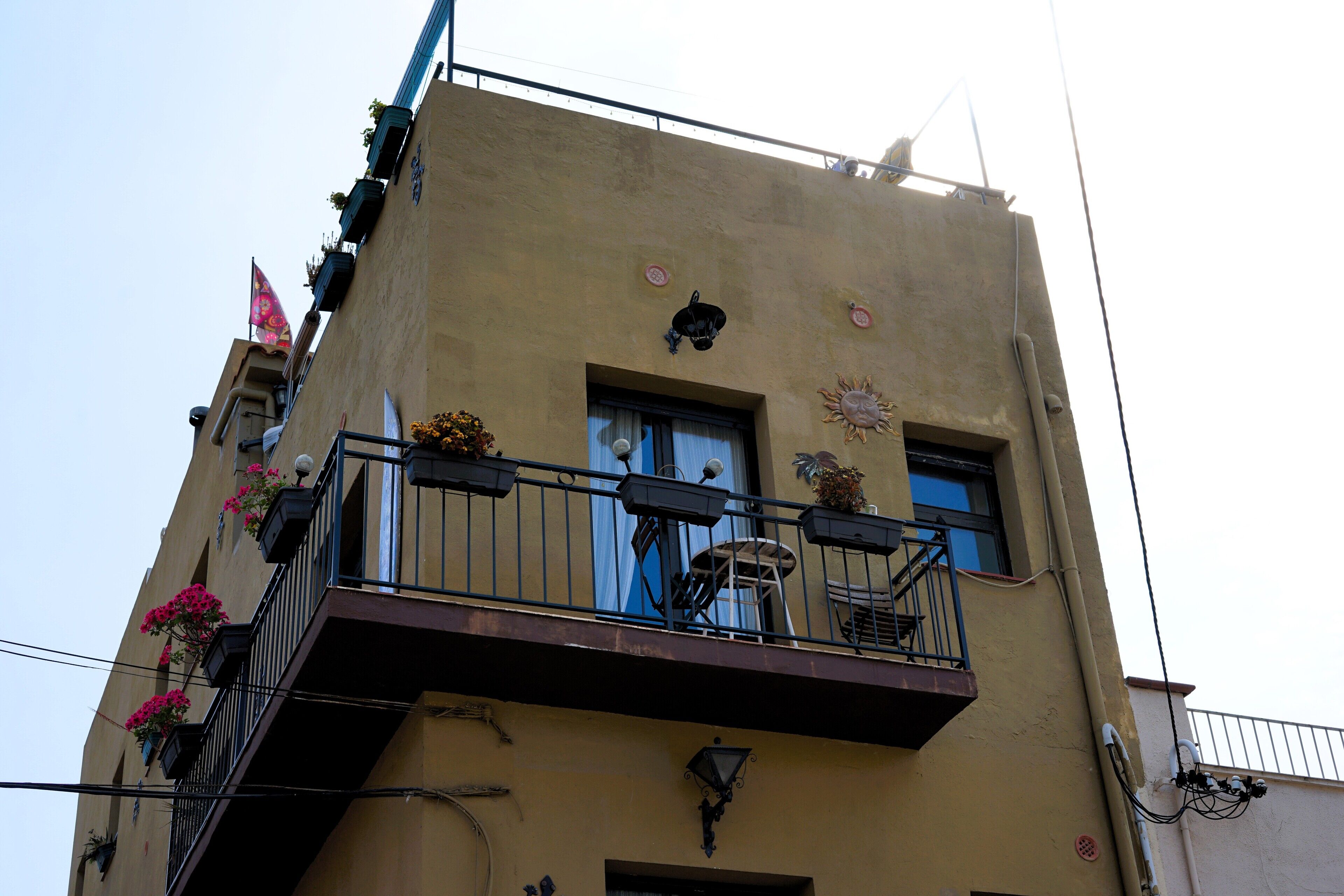 A multi-story building with balconies, windows, and outdoor lighting fixtures.