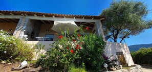 A building with a stone facade, a tiled roof, and a covered outdoor area with a white umbrella. - THE BALCONIES OF VALINCO La Vigie No. 5 (Olmeto)