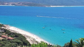 A coastal view with a beach, boats, and a distant shoreline.