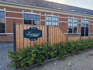 Un bâtiment en briques, avec une clôture en bois et une enseigne indiquant « Logement du 12e étage ».