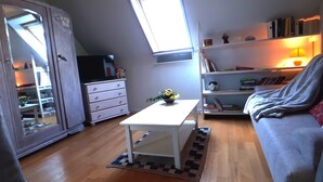 A cozy room with a white table, a sofa, a bookshelf, and a TV on a dresser. - Cozy gite 3 *, 2 to 4 people, 1st floor in the house. Individual entrance. (67370 Berstett)