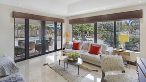 Amplia sala de estar con un sofá grande, una mesa de centro y vista a una piscina y zona de estar al aire libre.