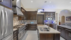 Una cocina moderna con alacenas de madera oscura, electrodomésticos de acero inoxidable, encimera de mármol y una isla integrada con pileta.