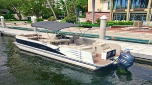 Un motorboat atracado en un puerto deportivo con una zona de estar cubierta, un motor fueraborda Yamaha y una zona de piscina con una estatua.