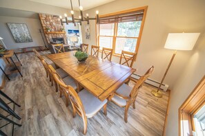 A dining area with a wooden table and chairs, a stone fireplace, and a large window with a view.