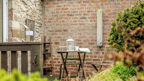 An outdoor patio with a brick wall, wooden furniture, and a lantern. - 1 bedroom accommodation in Middleton-by-Wirksworth, near Wirksworth (Middleton-by-Wirksworth, near Wirksworth)