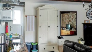 A kitchen with a white cabinet, a dining area with a table set for two, and a black sofa. - 1 bedroom accommodation in Middleton-by-Wirksworth, near Wirksworth (Middleton-by-Wirksworth, near Wirksworth)