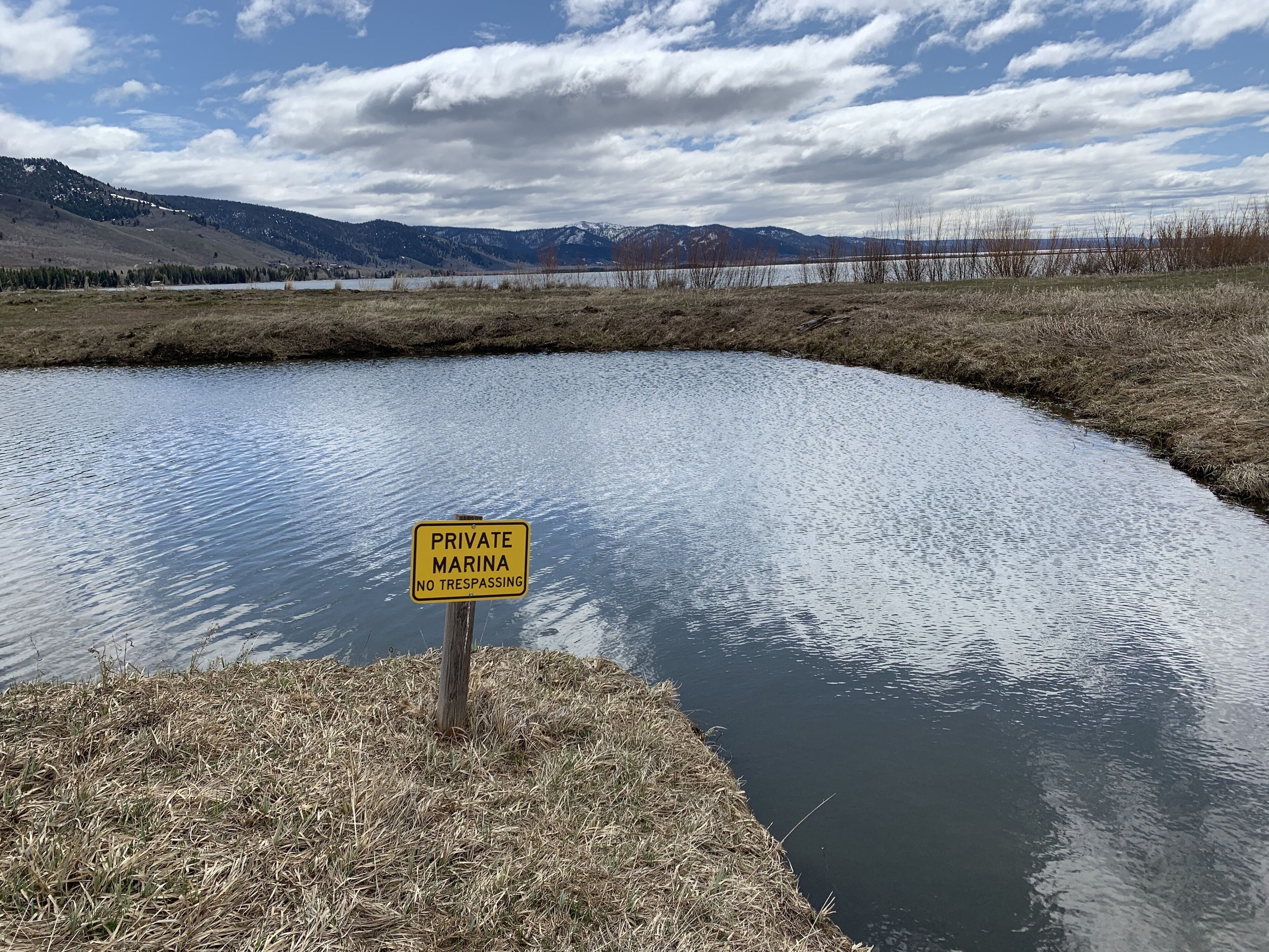 A private marina with a no trespassing sign, surrounded by a natural landscape with mountains in the background.