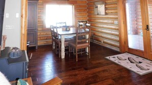 Ein Holzblockhaus-Interieur mit Essbereich, Deckenventilator und Kamin.
