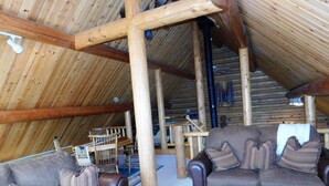 Ein gemütliches Blockhaus-Interieur mit zwei Sofas, einem Couchtisch und einer Holztreppe.