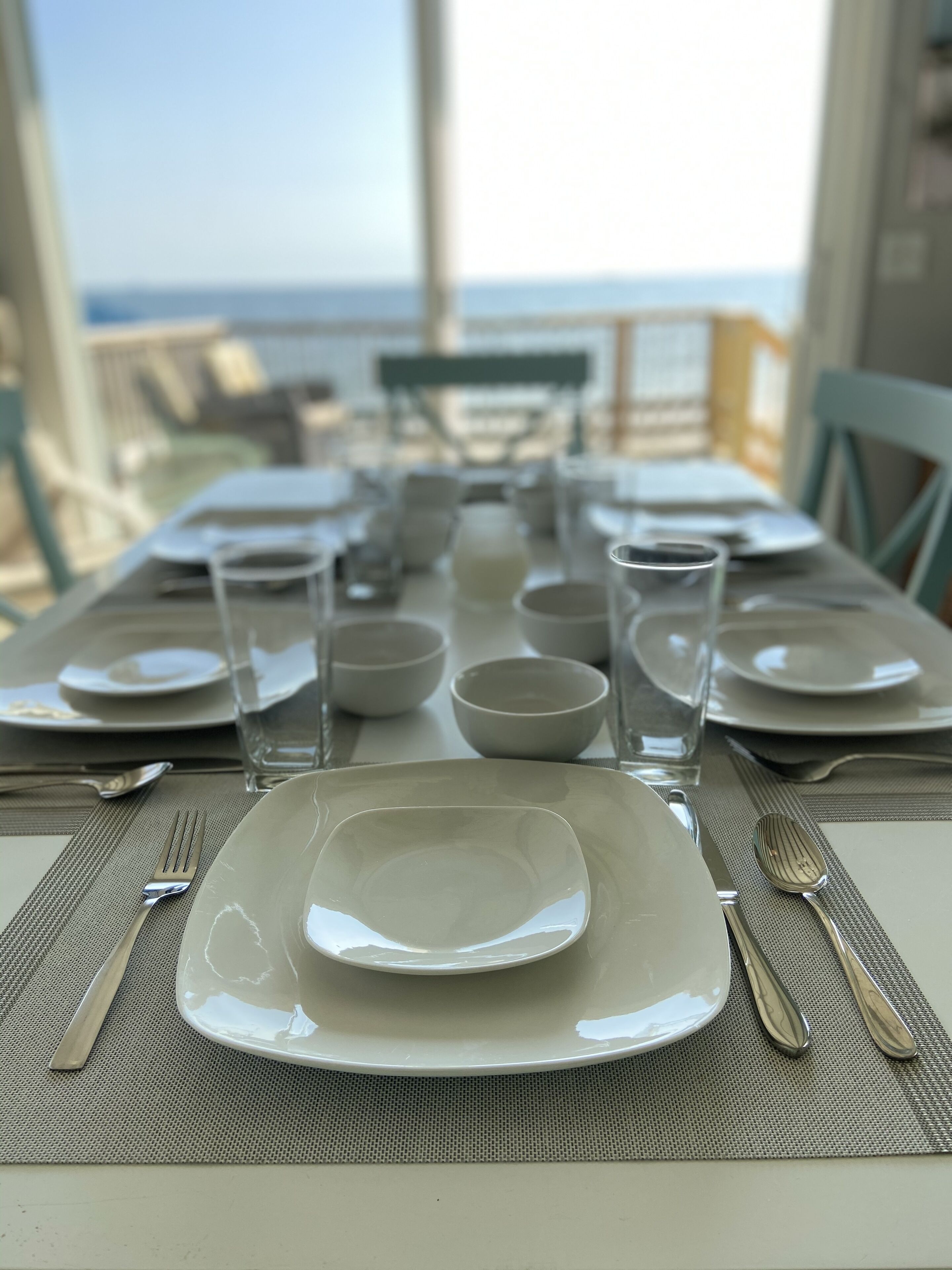 A table set for a meal with plates, bowls, glasses, and cutlery.