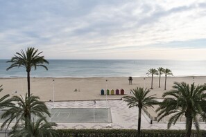 Uma praia com palmeiras, uma área arenosa e uma fileira de cabanas de praia coloridas.