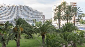 Een hotel met een groot, gebogen gebouw en palmbomen op de voorgrond.