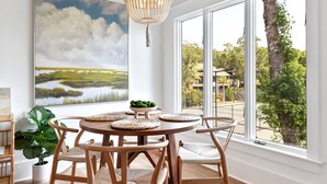 Un comedor con una mesa redonda, sillas de madera y un amplio ventanal con vistas a árboles y un edificio.
