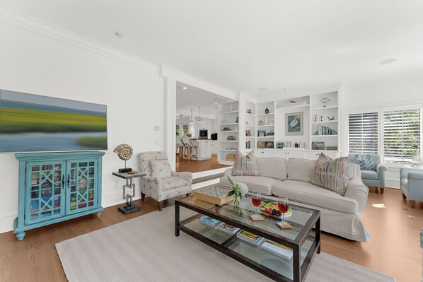 A modern living room with a sofa, armchairs, a coffee table, and a bookshelf. - Spacious home, easy beach access (Kiawah Island)