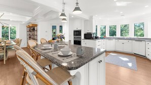 Una cocina amplia con armarios blancos, encimeras de granito y una isla grande con asientos.
