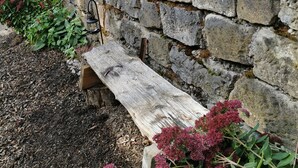 A rustic stone wall with a wooden bench.