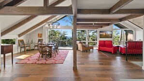 An open-plan living area with a dining table, chairs, and a red sofa. - Pebble Beach's Empire (Pebble Beach)