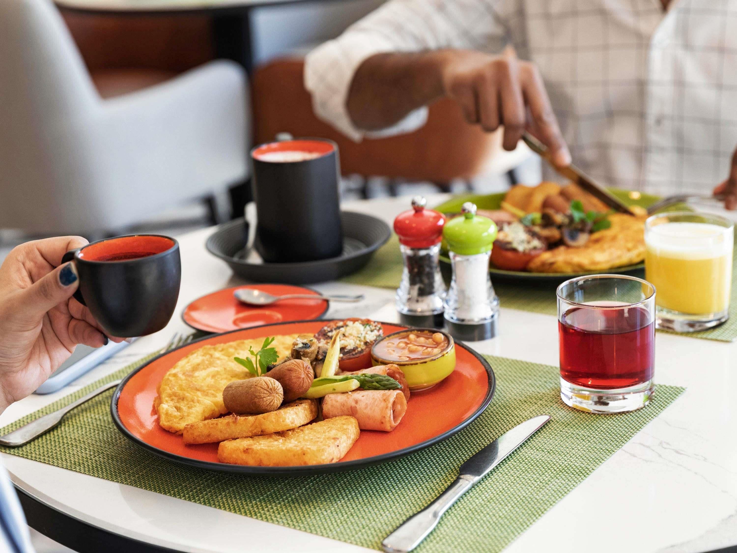 A breakfast setting with a plate of food, a cup, and a glass of juice.