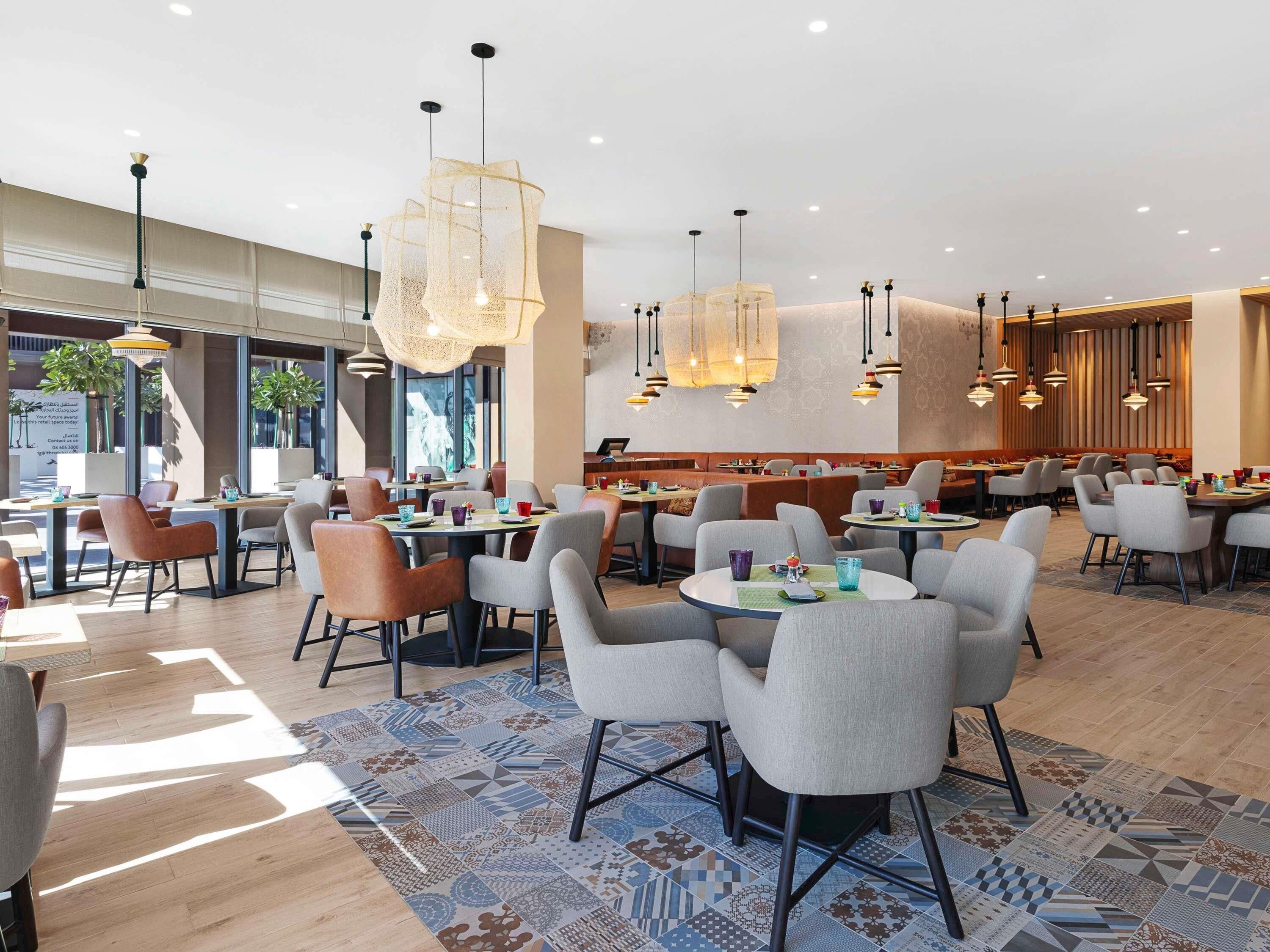 A modern restaurant interior with round tables, chairs, and pendant lighting.
