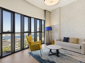 Un salon moderne avec une grande fenêtre, un fauteuil jaune, un canapé blanc et une table basse ronde.