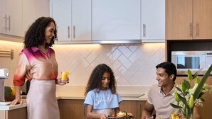 A modern kitchen with white cabinets, a Bosch refrigerator, and a dining area with a table set for three. - Aparthotel Adagio Dubai Gold District (Dubai)