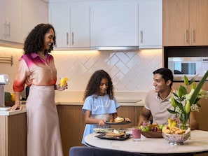 Una cocina moderna con armarios blancos, un refrigerador Bosch y una zona de comedor con mesa dispuesta para tres.