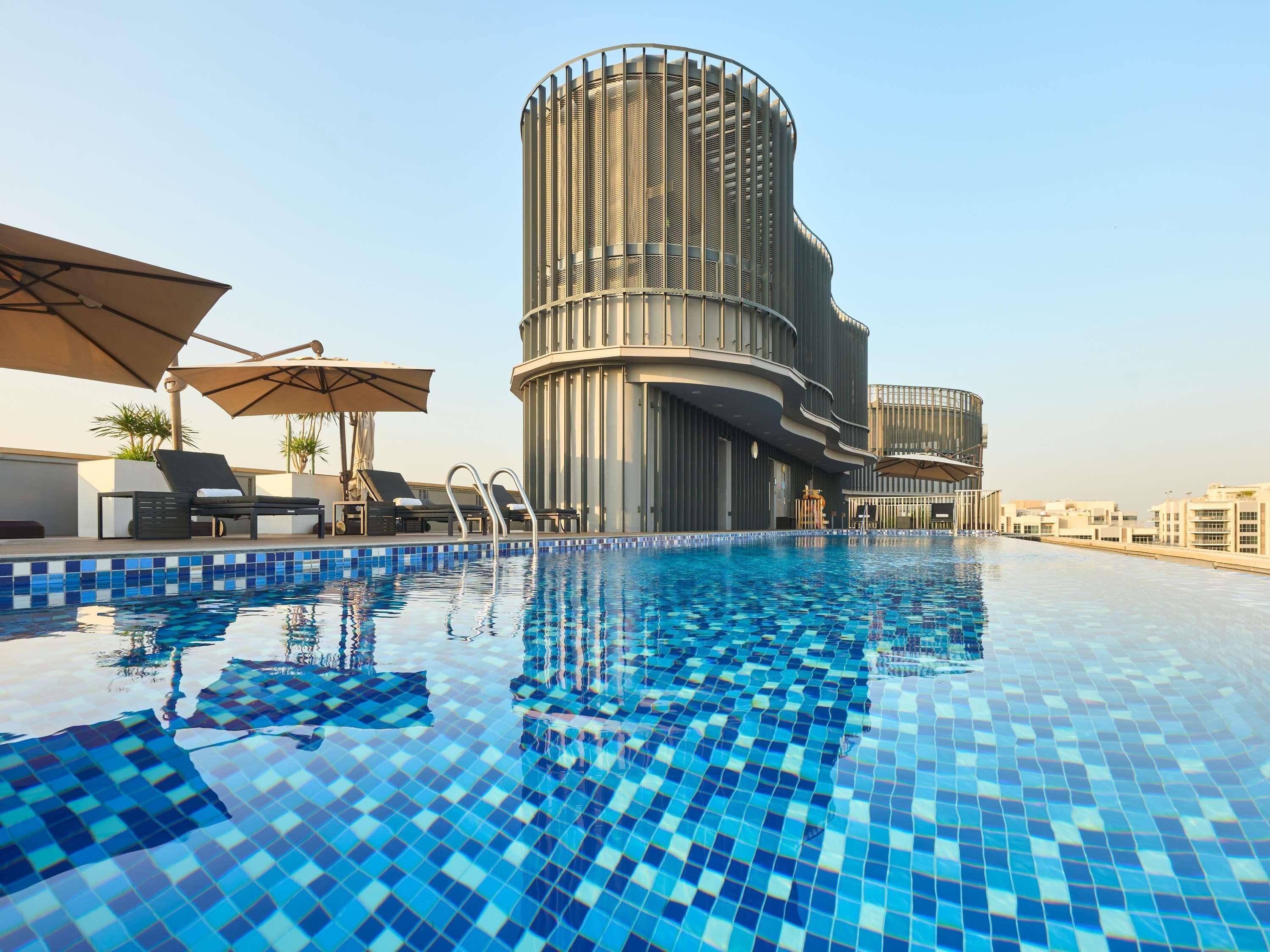 A rooftop swimming pool with a modern building in the background.
