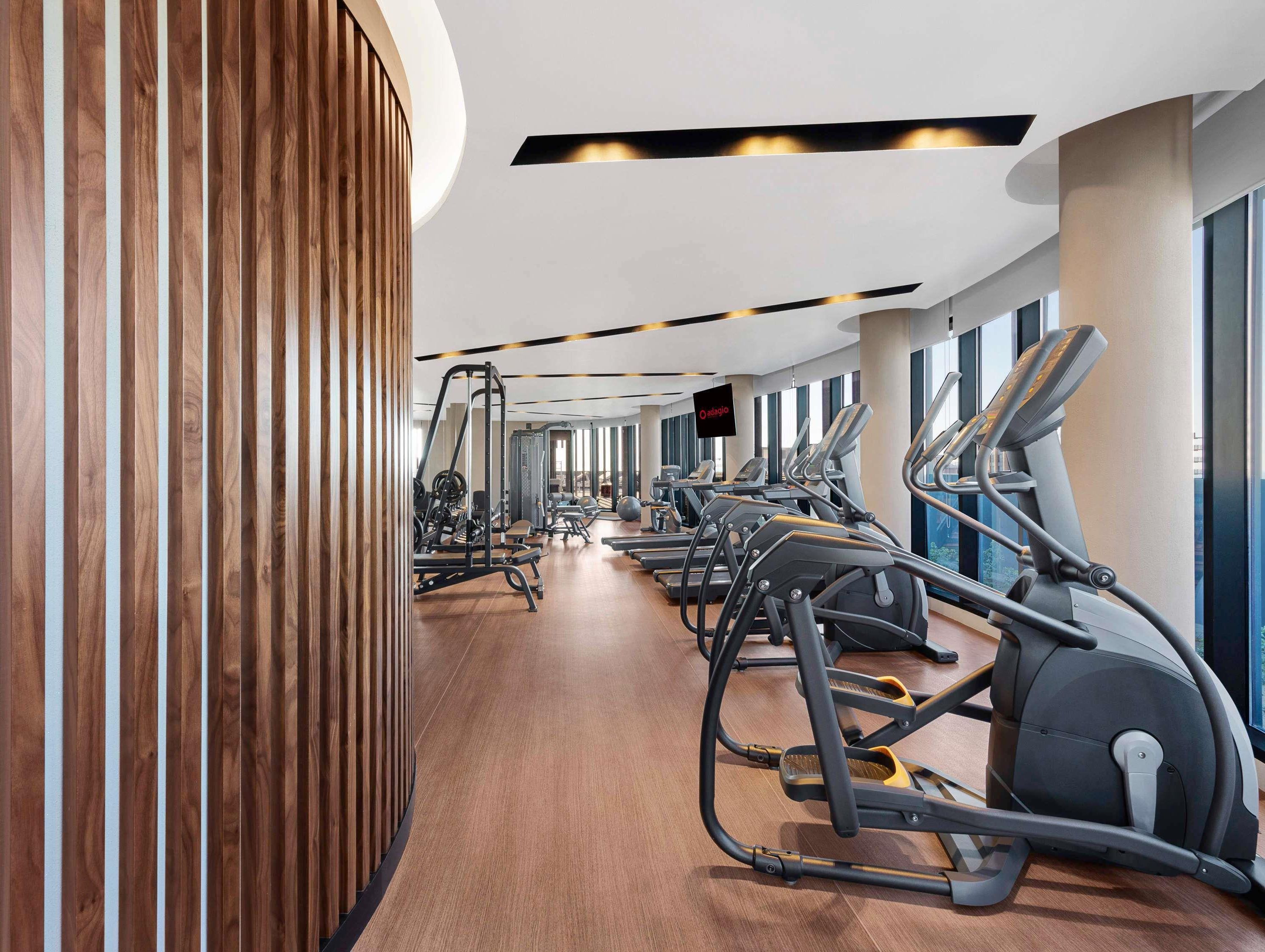 Une salle de sport équipée de matériel d’exercice, dotée de lambris en bois et de grandes fenêtres.
