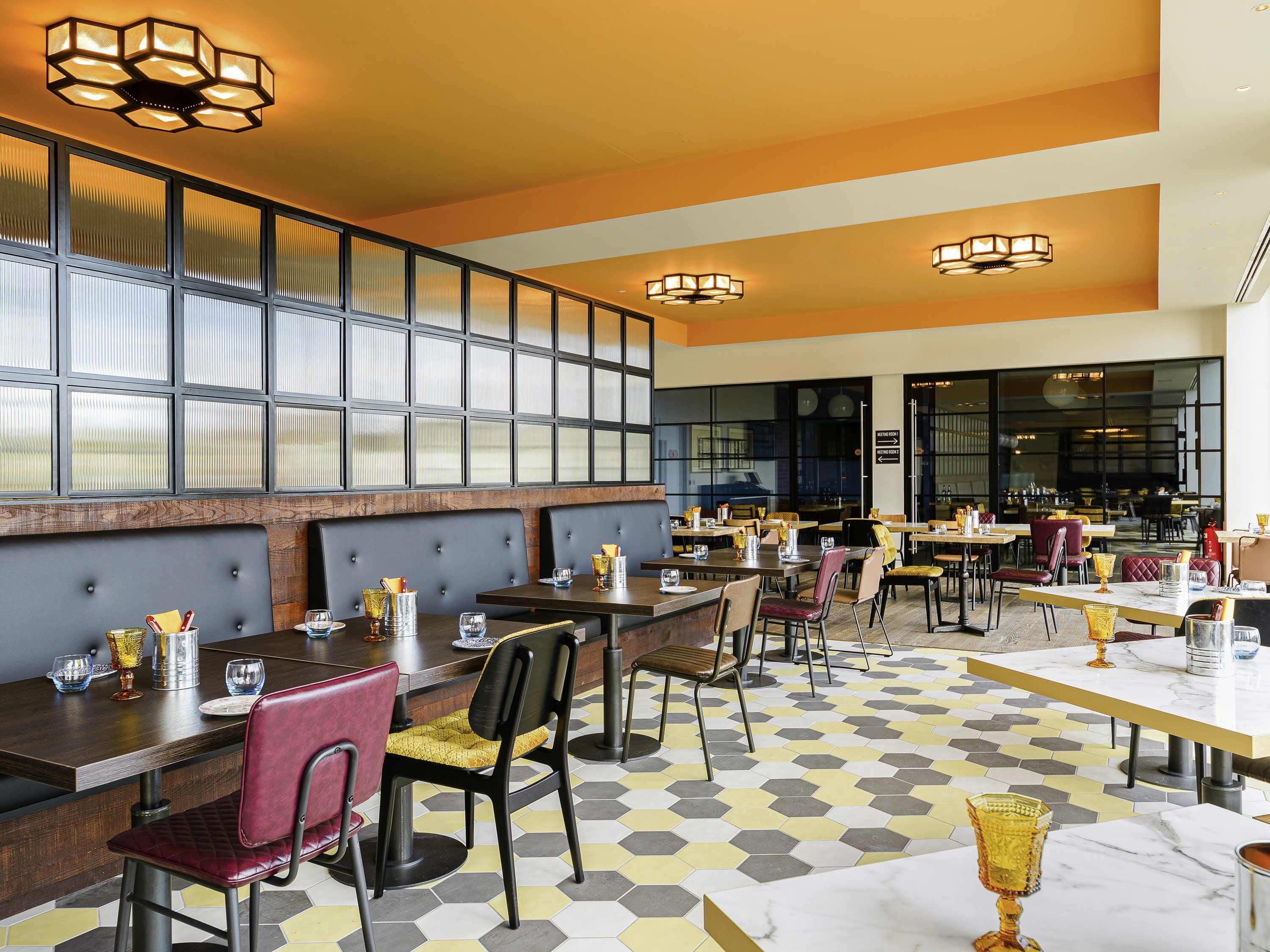 A restaurant with hexagonal patterned flooring, dark wooden tables, and cushioned chairs.