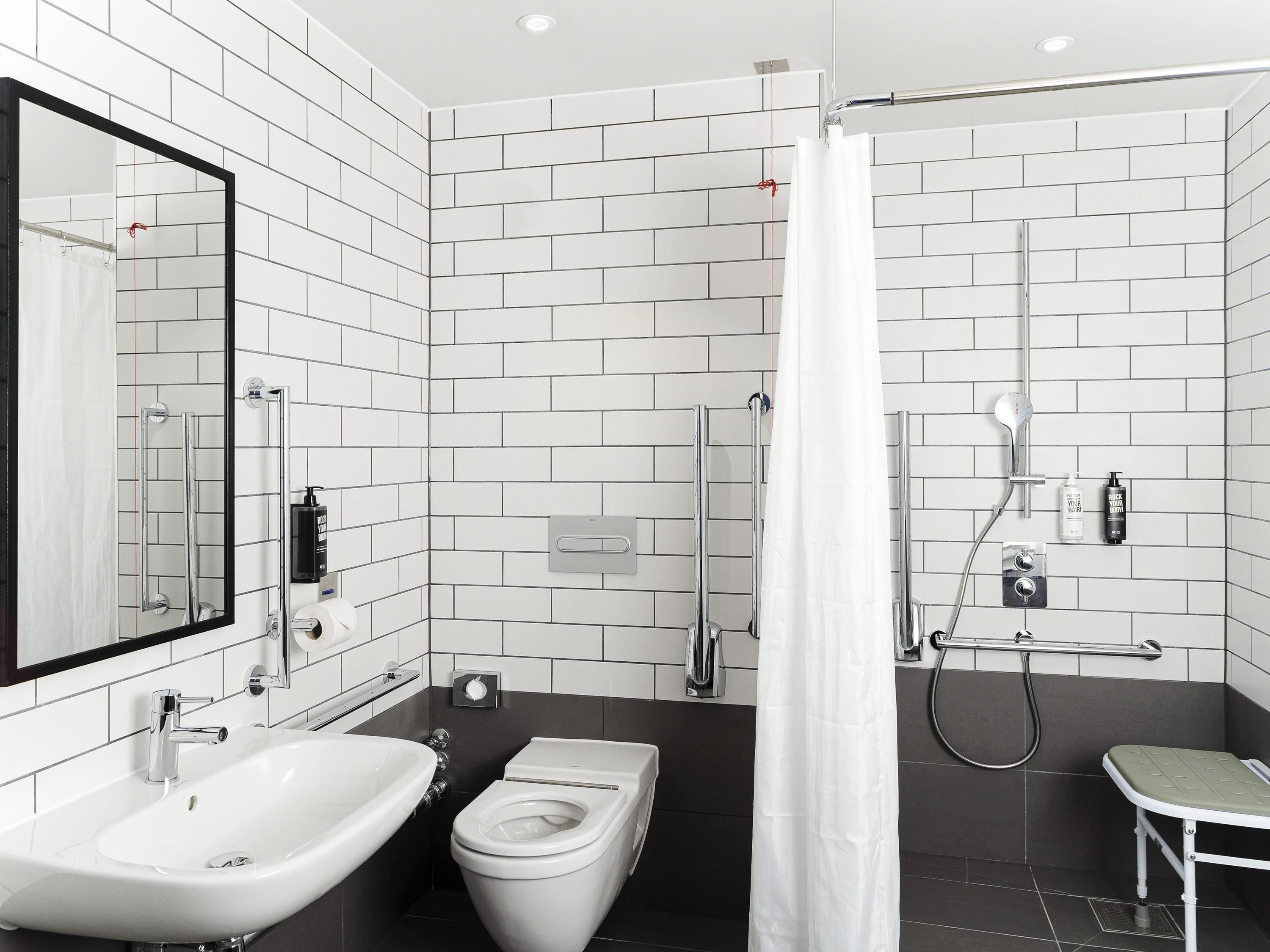 Un baño moderno con lavamanos, inodoro y zona de ducha blancos.