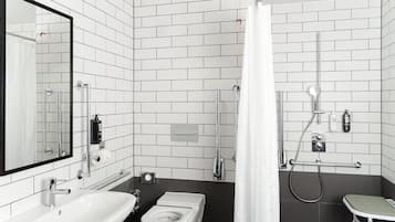 Un baño moderno con lavamanos, inodoro y zona de ducha blancos.