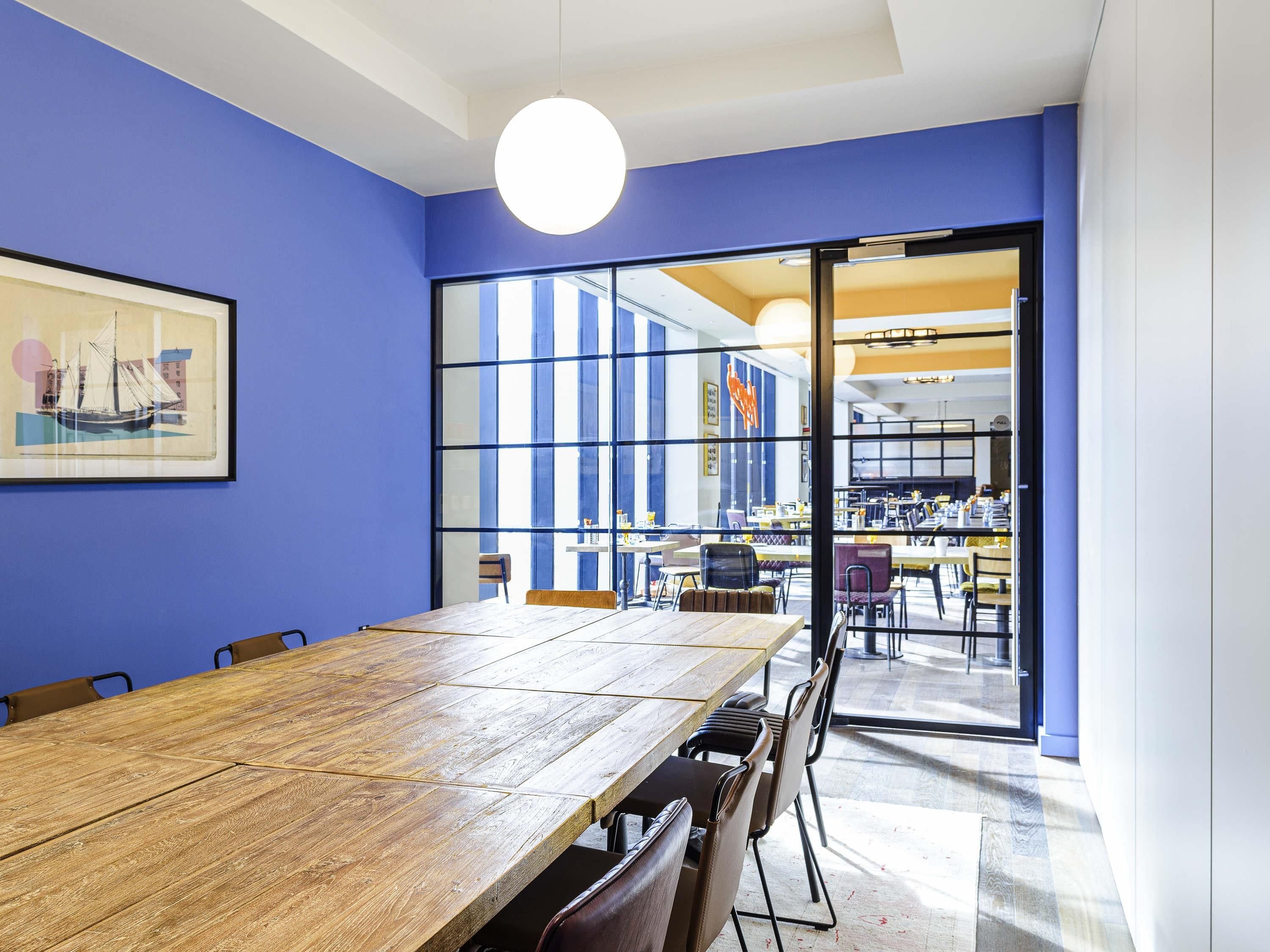 A conference room with a wooden table, chairs, and a large window.
