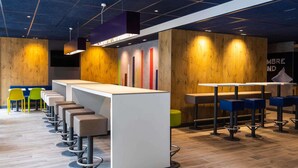 Un espace bar moderne avec un long comptoir, de nombreux tabourets et un mur d’accent en bois.