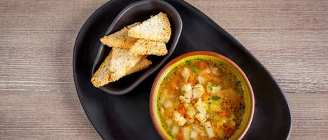 A bowl of soup with croutons on a black plate.